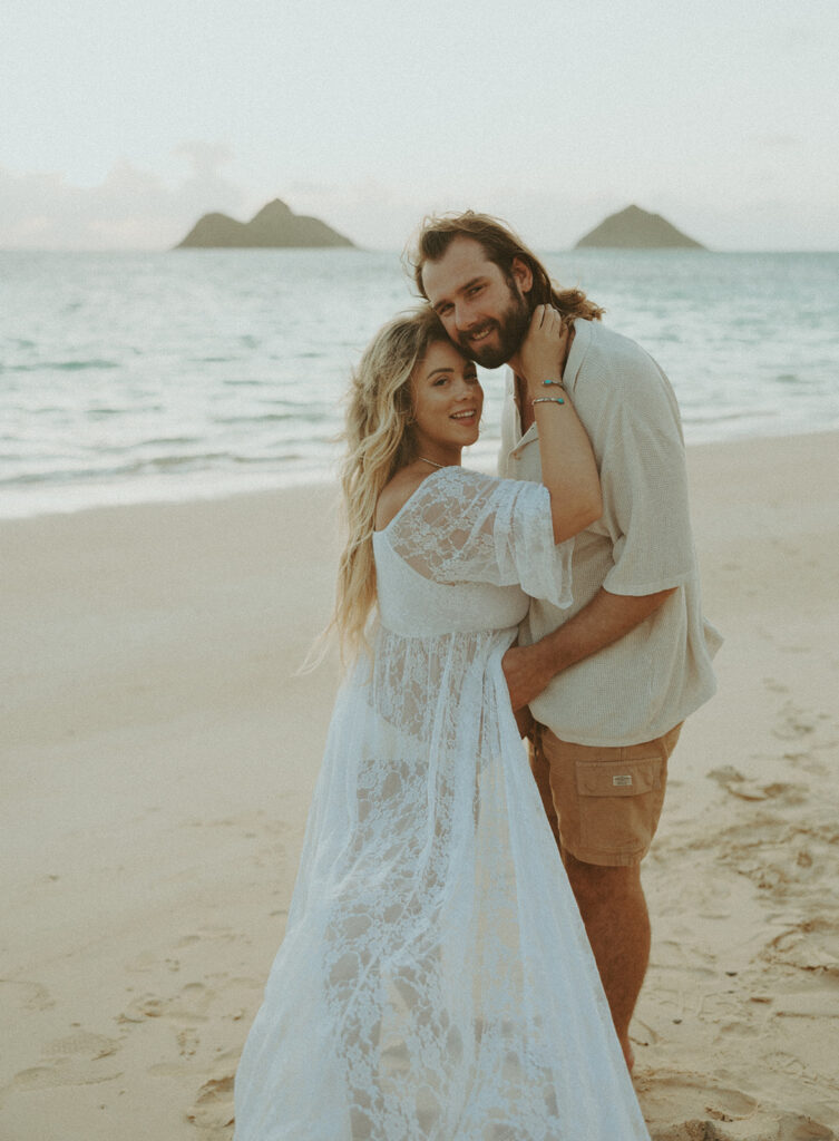 a maternity photoshoot in oahu hawaii with a couple playing on the beach and in the ocean
