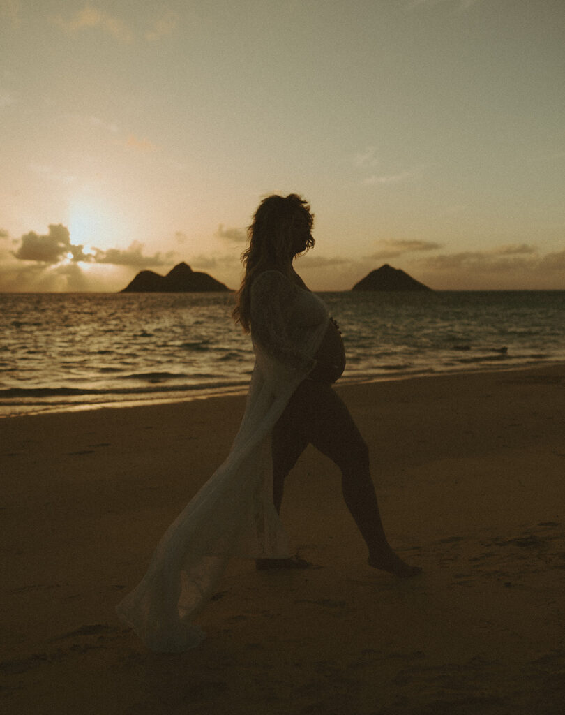a carefree couple posing for a maternity session on a beach in oahu
