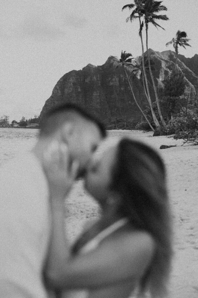 a couple posing for an engagement photoshoot on the beach in oahu
