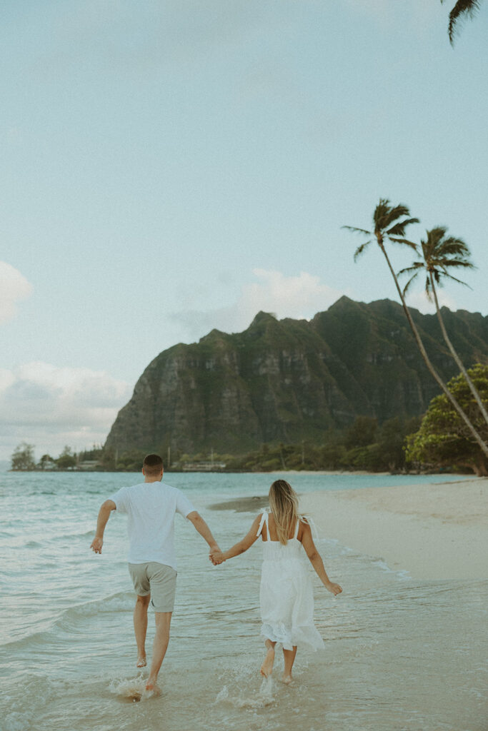 a couple posing for an engagement photoshoot on the beach in oahu