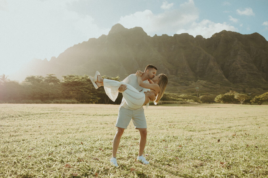 a couple posing in an open field in Oahu for their engagement photos