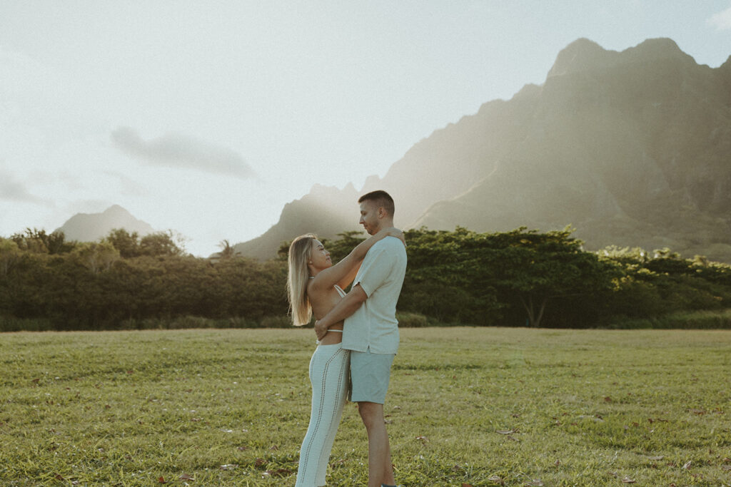 a couple posing in an open field in Oahu for their engagement photos
