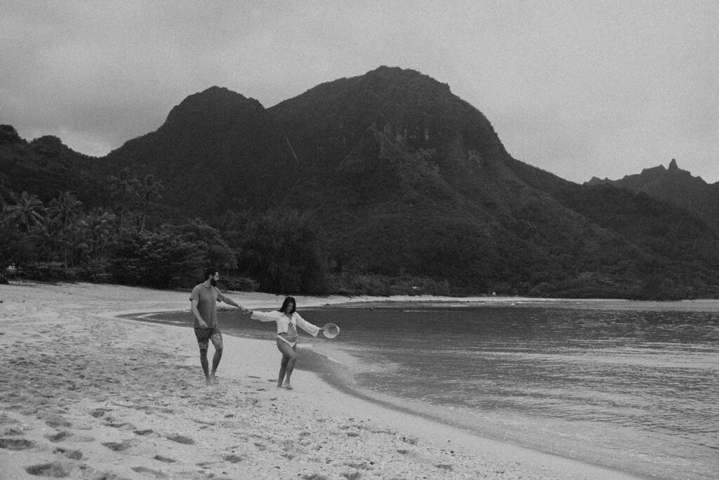 a couples posing on a beach in kauai for their maternity photoshoot

