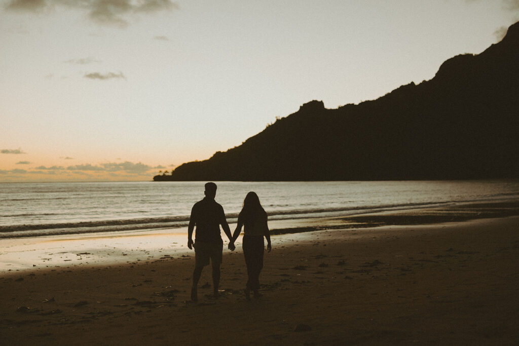 A couple posing on the beaches of hawaii for a honeymoon photoshoot

