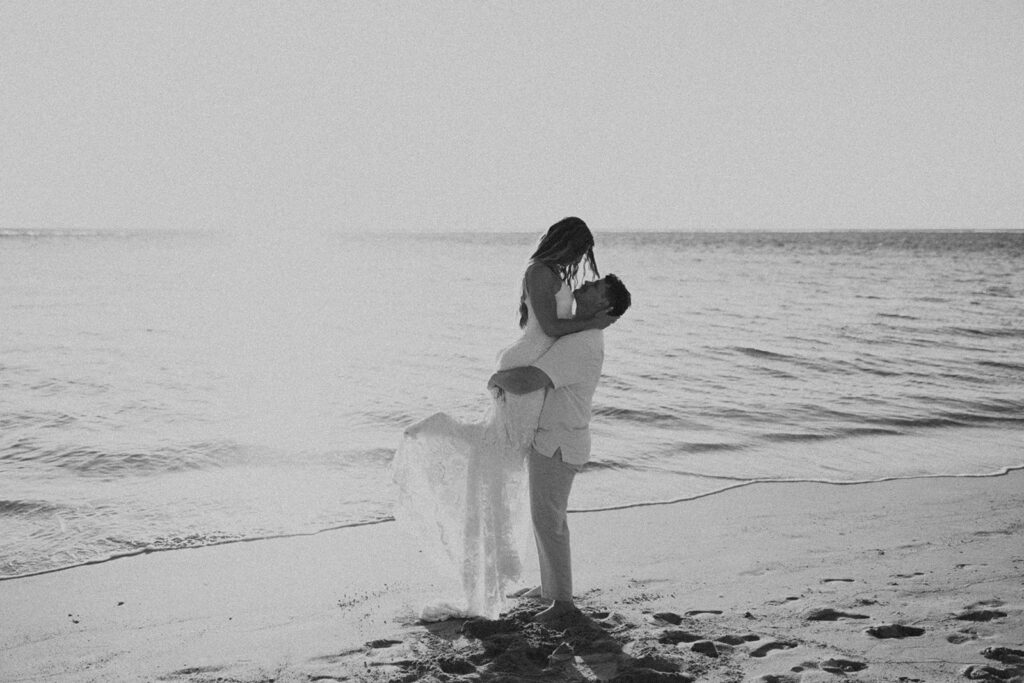 bride and groom posing on the beach for their wedding photos
