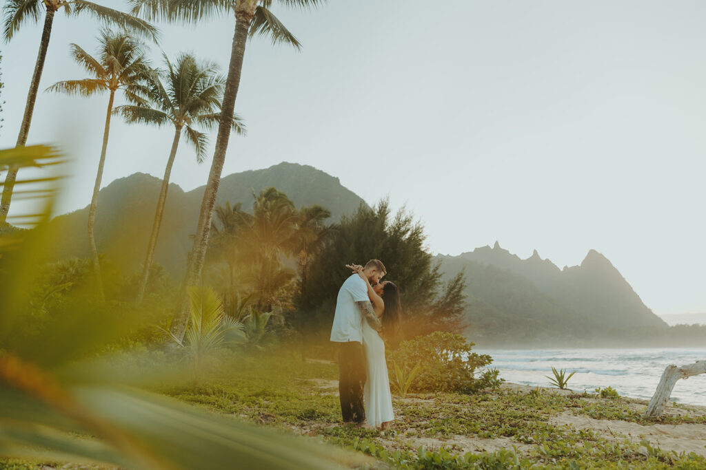 Couple standing together on Tunnels Beach at sunset
