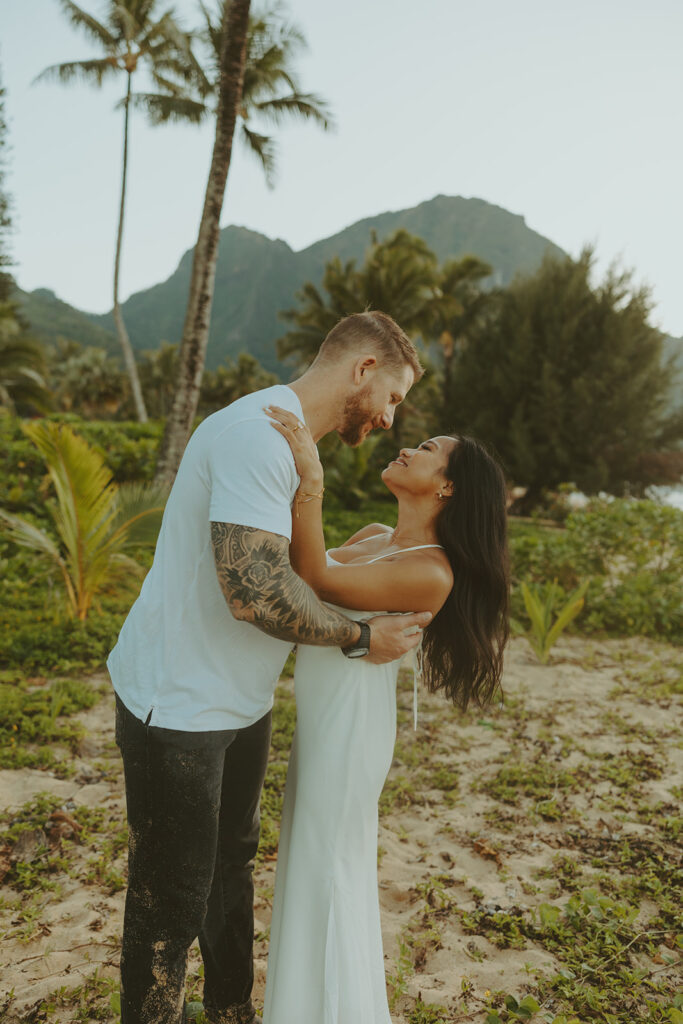 Couple standing together on Tunnels Beach at sunset
