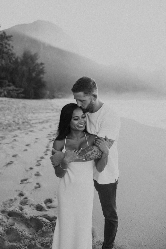 Couple standing together on Tunnels Beach at sunset
