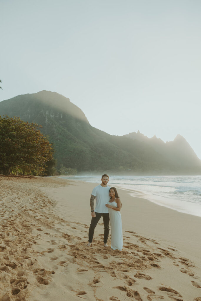 Couple standing together on Tunnels Beach at sunset
