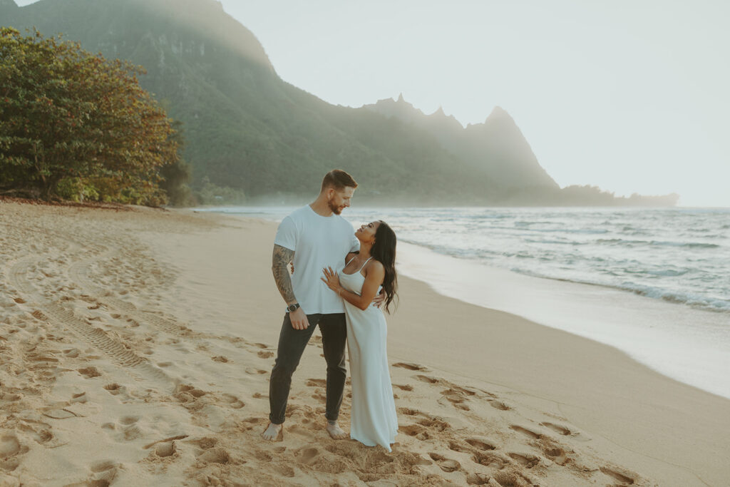Couple standing together on Tunnels Beach at sunset