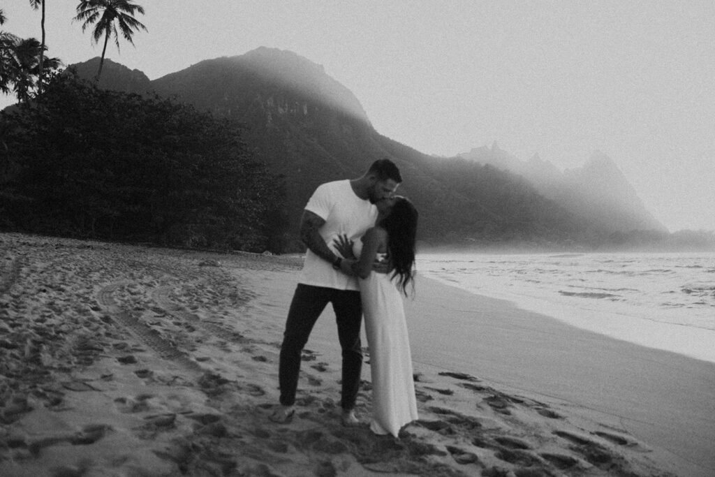 Couple standing together on Tunnels Beach at sunset
