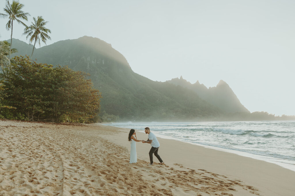 Couple standing together on Tunnels Beach at sunset
