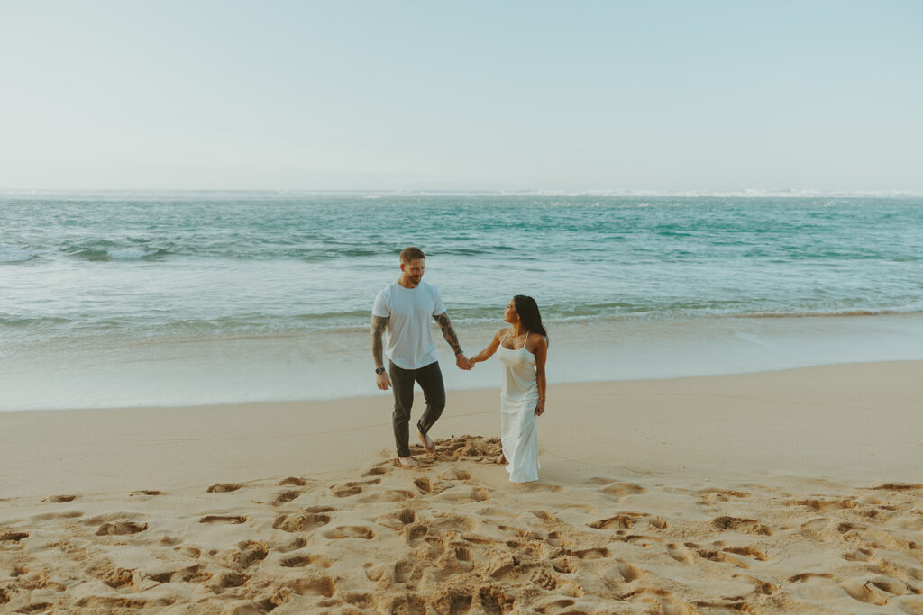 Candid moment of couple walking along the shoreline at Tunnels Beach
