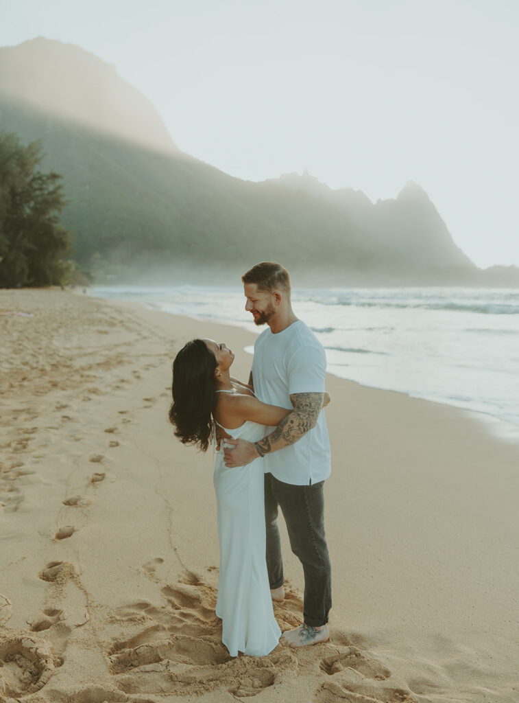 Couple standing together on Tunnels Beach at sunset
