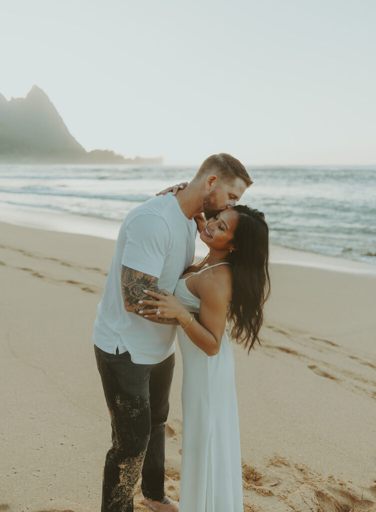 Engaged couple hugging and laughing during beach photoshoot
