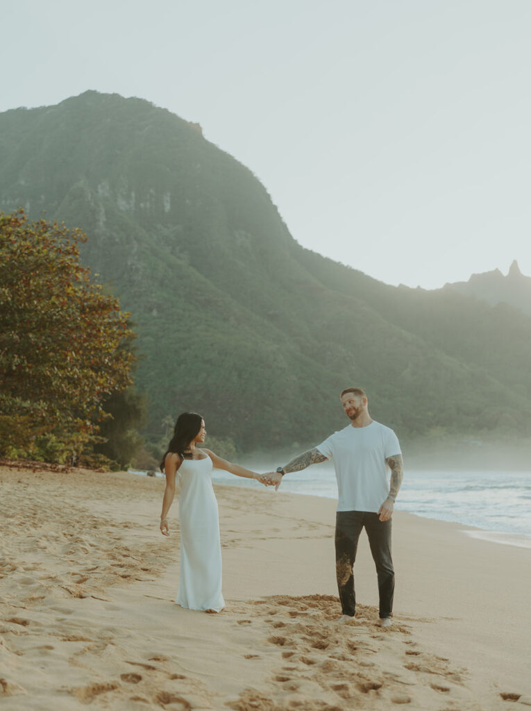 Candid moment of couple walking along the shoreline at Tunnels Beach
