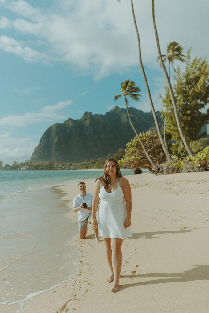 Nicholas down on one knee proposing to Nicole on a beach in Hawaii.
