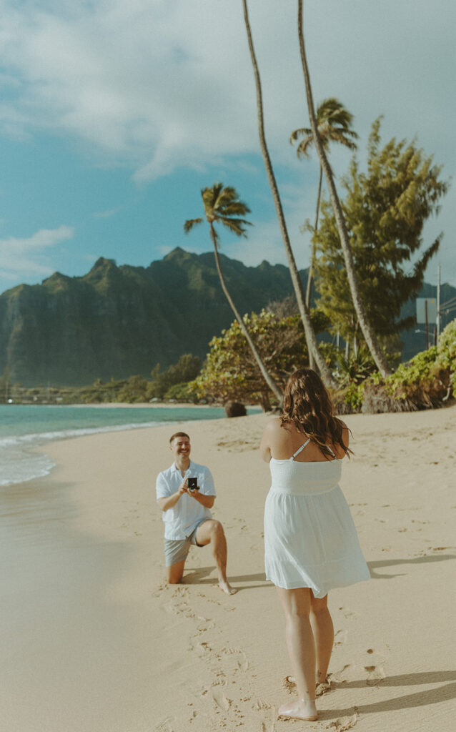 Nicholas down on one knee proposing to Nicole on a beach in Hawaii.
