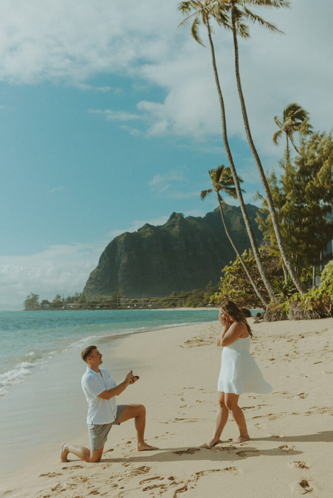 Nicholas down on one knee proposing to Nicole on a beach in Hawaii.
