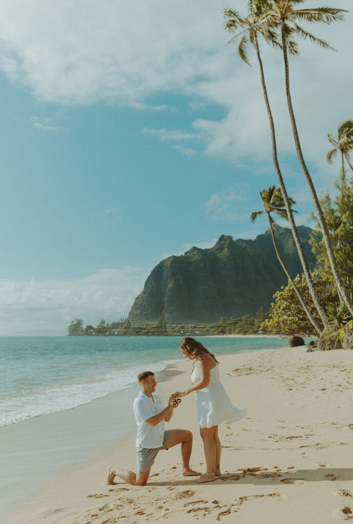 Nicholas down on one knee proposing to Nicole on a beach in Hawaii.
