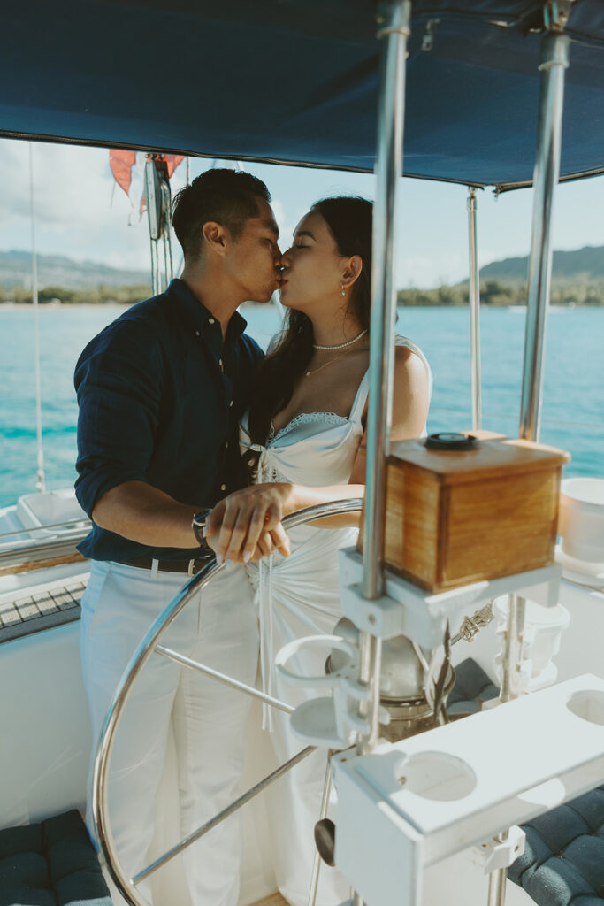 Romantic couple embracing on a sailboat during a Waikiki sailboat photoshoot in Oahu, Hawaii

