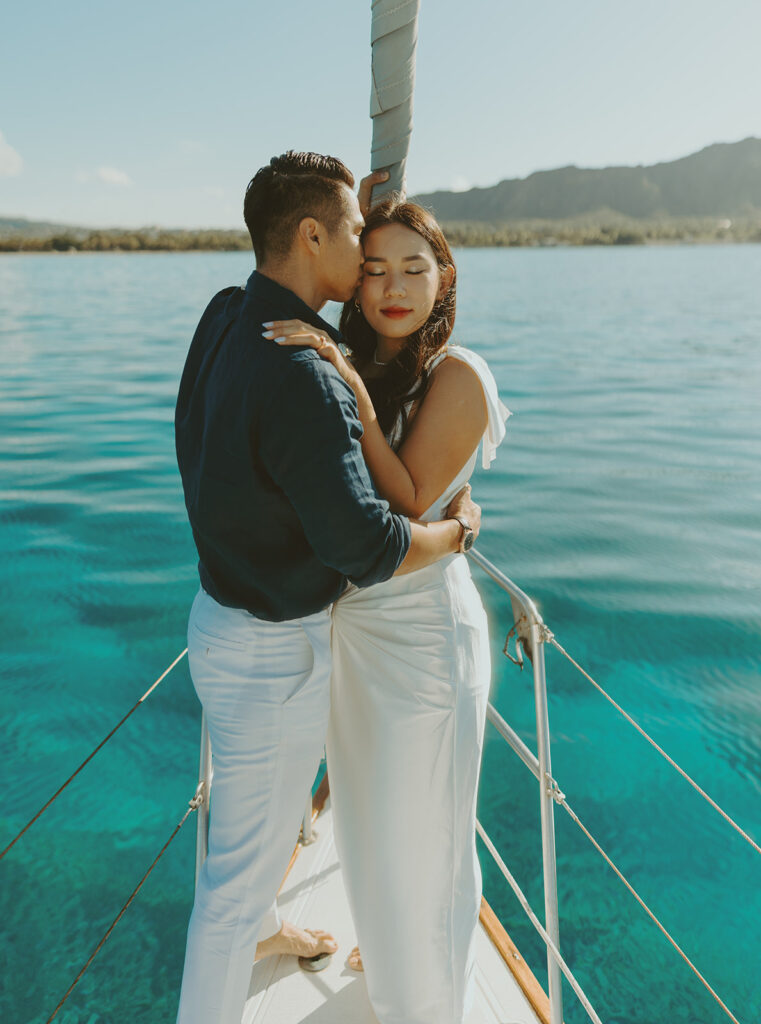 Romantic couple embracing on a sailboat during a Waikiki session in Oahu, Hawaii
