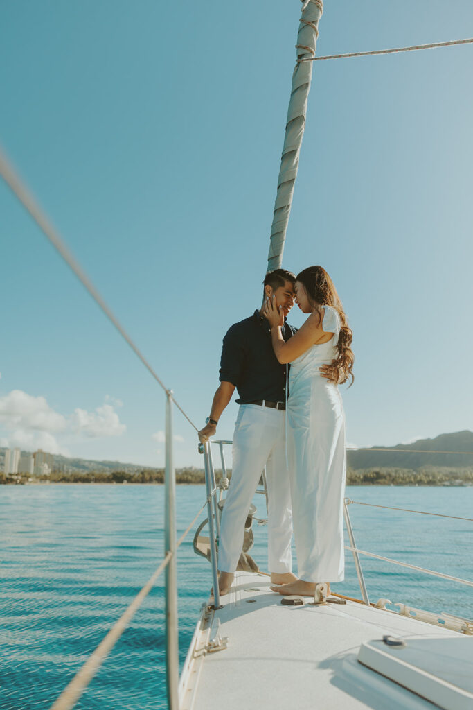 Romantic couple embracing on a sailboat during a Waikiki sailboat photoshoot in Oahu, Hawaii
