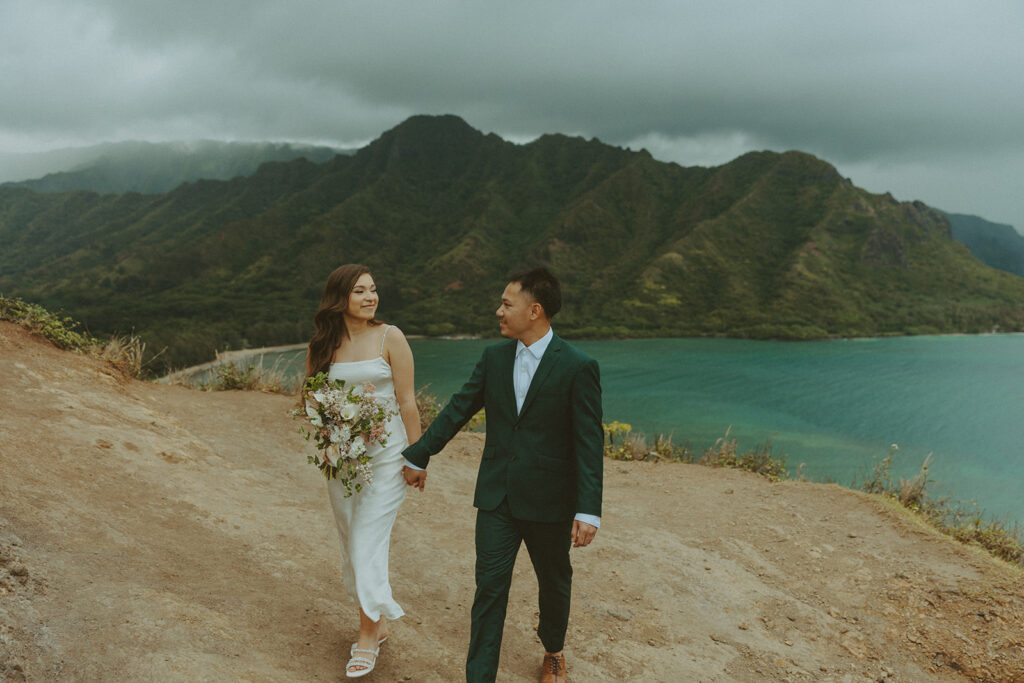 Couple standing together at the top of Crouching Lion hike with ocean views in the background
