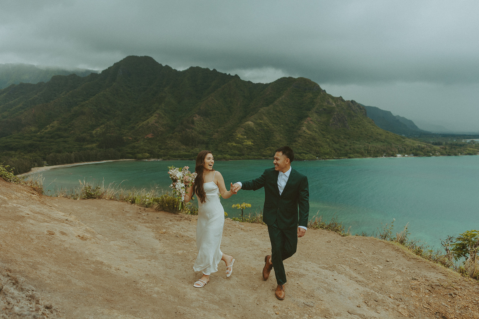 Couple standing together at the top of Crouching Lion hike with ocean views in the background
