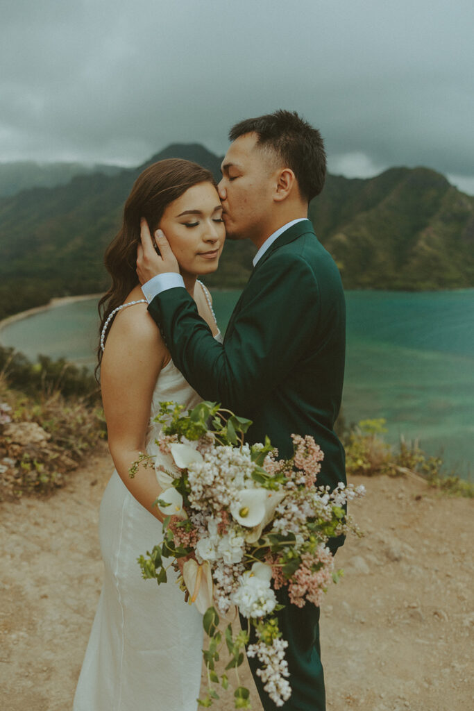 Couple standing together at the top of Crouching Lion hike with ocean views in the background
