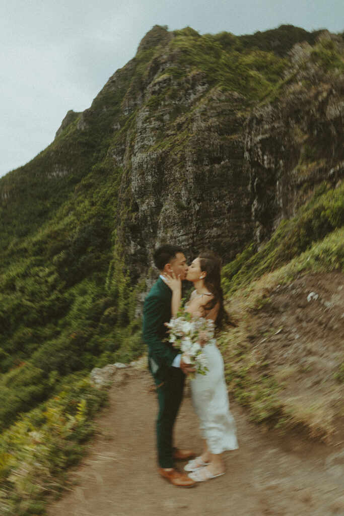 Couple standing together at the top of Crouching Lion hike with ocean views in the background
