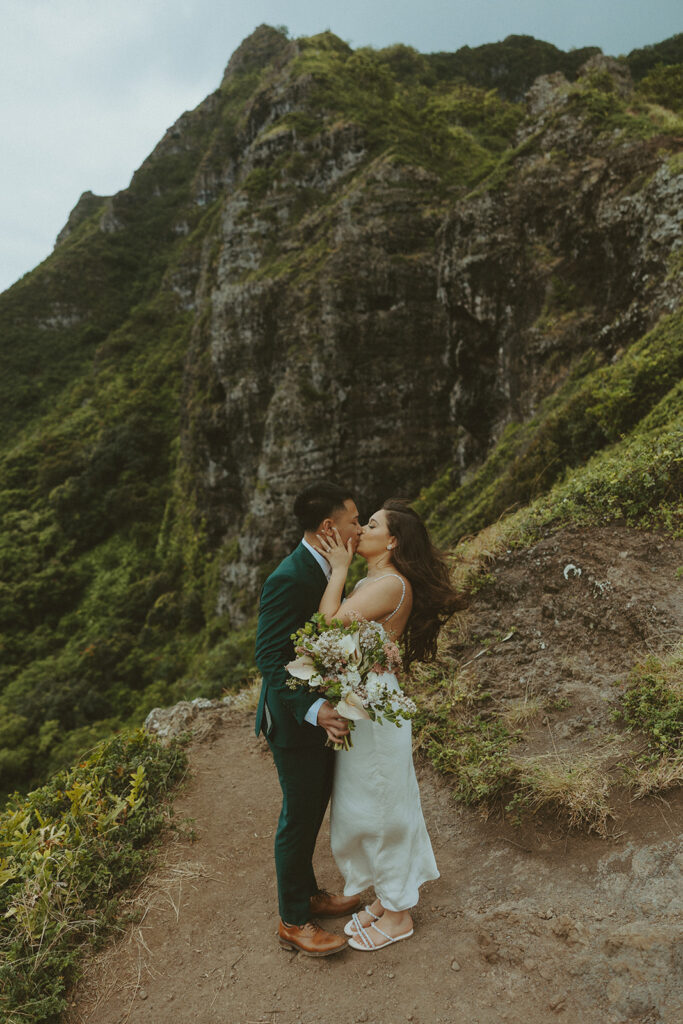 Couple standing together at the top of Crouching Lion hike with ocean views in the background
