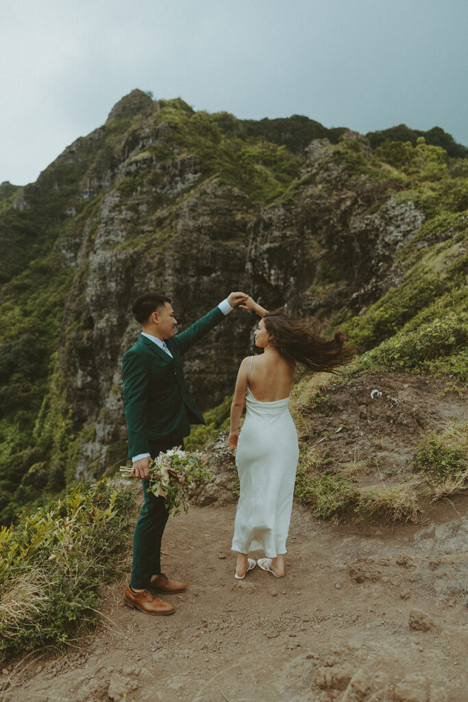 Couple standing together at the top of Crouching Lion hike with ocean views in the background
