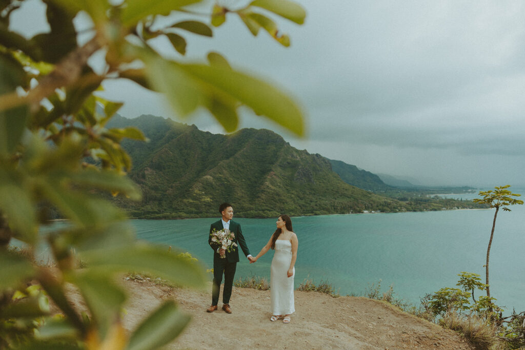 Couple standing together at the top of Crouching Lion hike with ocean views in the background

