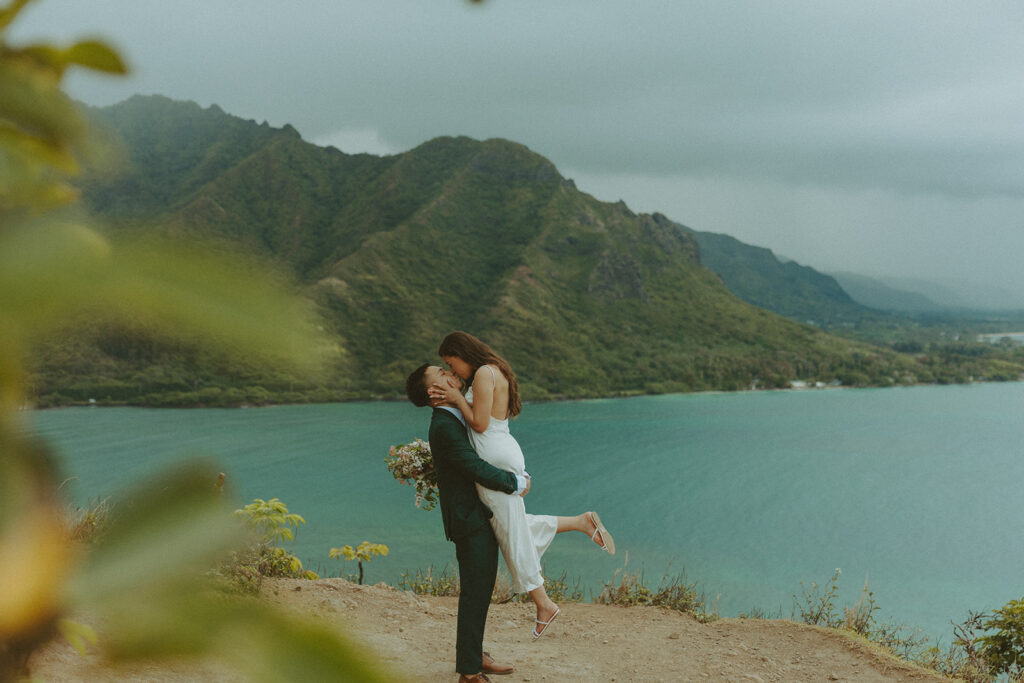 Couple standing together at the top of Crouching Lion hike with ocean views in the background
