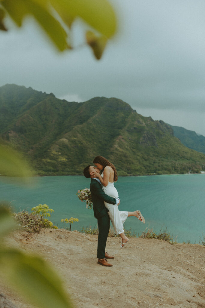 Couple standing together at the top of Crouching Lion hike with ocean views in the background
