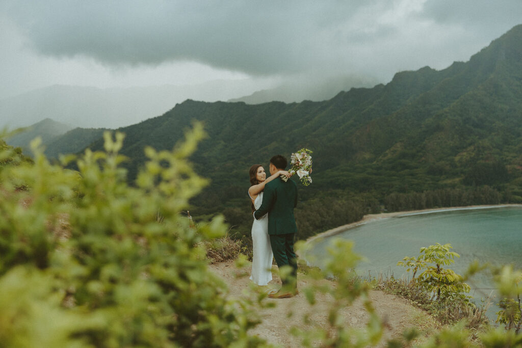 Couple standing together at the top of Crouching Lion hike with ocean views in the background
