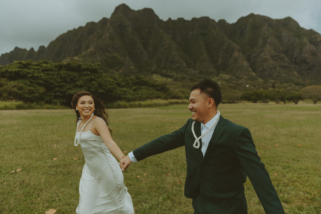 Couple holding hands while hiking through lush greenery on Oahu trail
