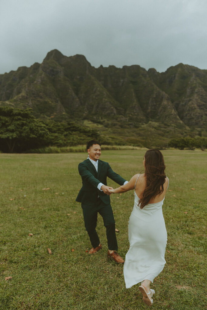 Couple holding hands while hiking through lush greenery on Oahu trail
