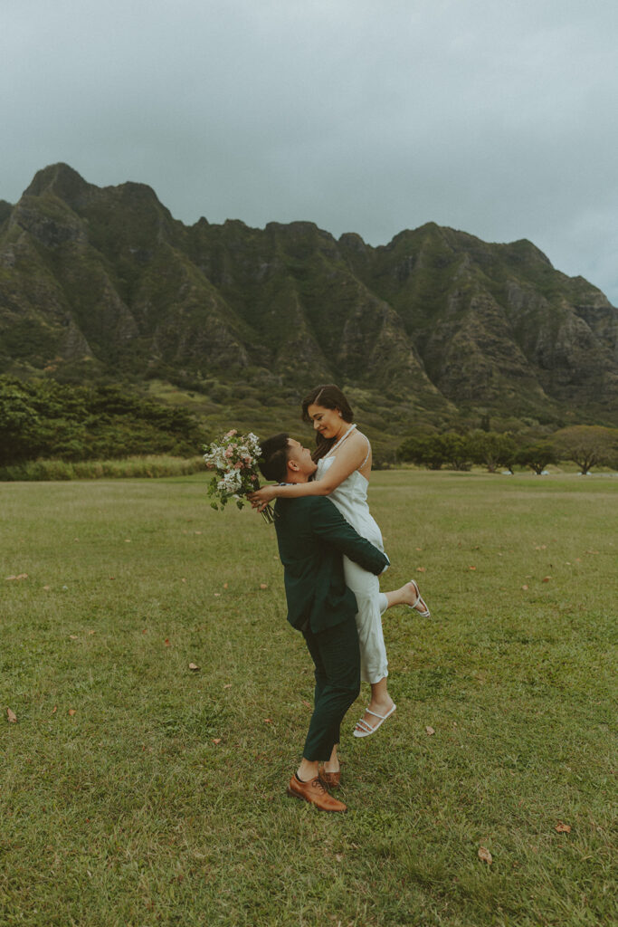 Couple holding hands while hiking through lush greenery on Oahu trail
