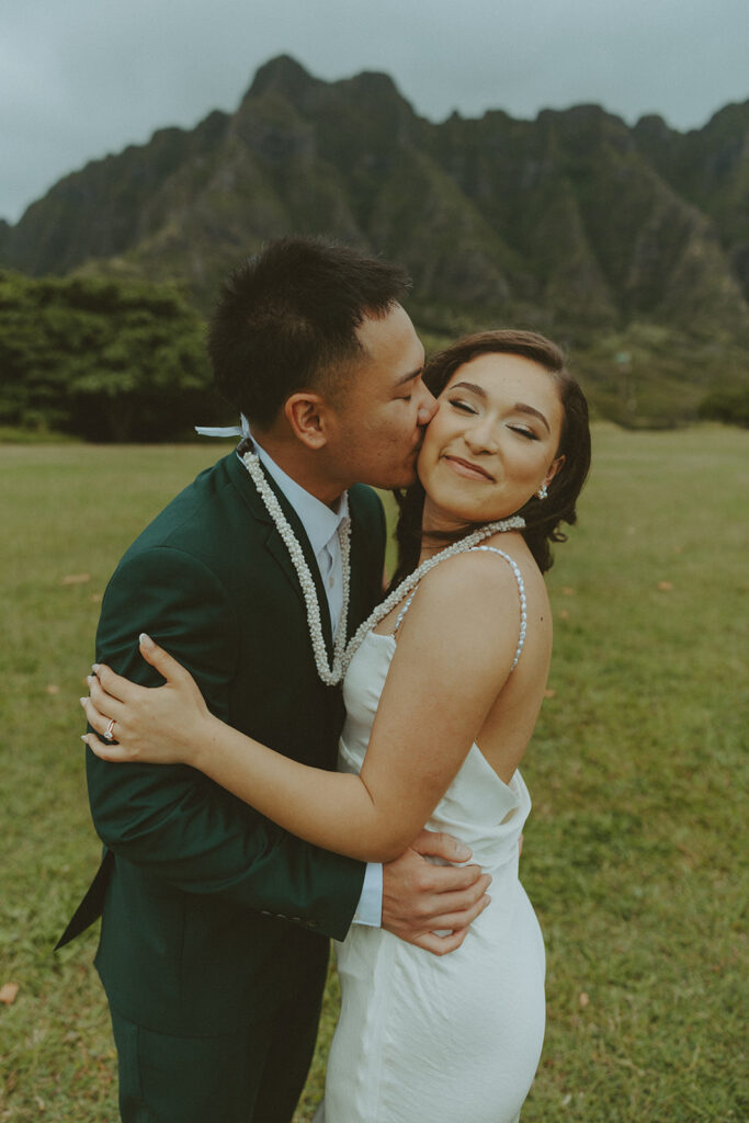 Couple holding hands while hiking through lush greenery on Oahu trail
