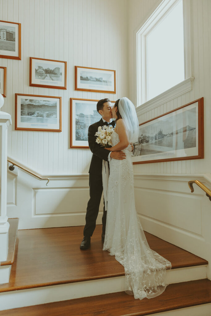 Couple sharing a kiss indoors during their wedding day.
