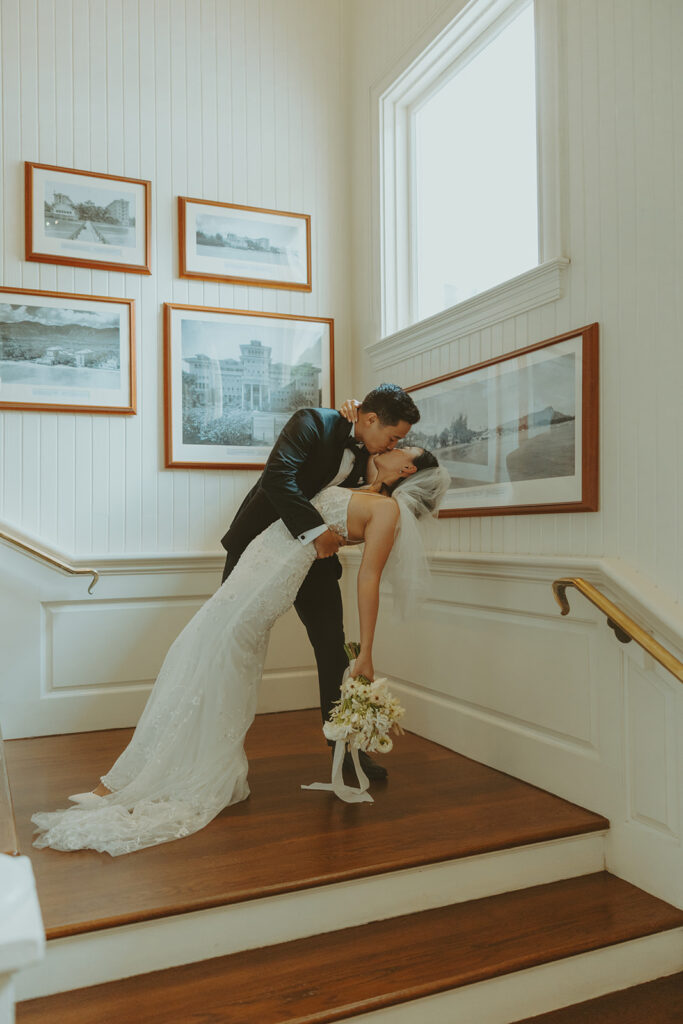 Couple sharing a kiss indoors during their wedding day.
