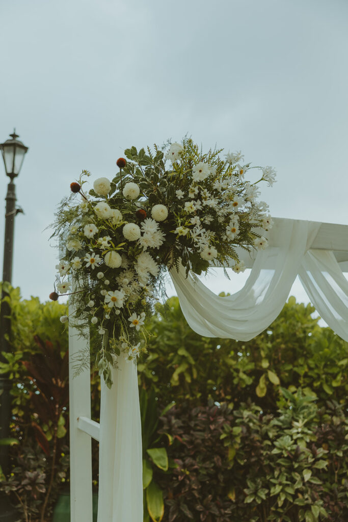 Outdoor wedding ceremony with palm trees and guests seated.
