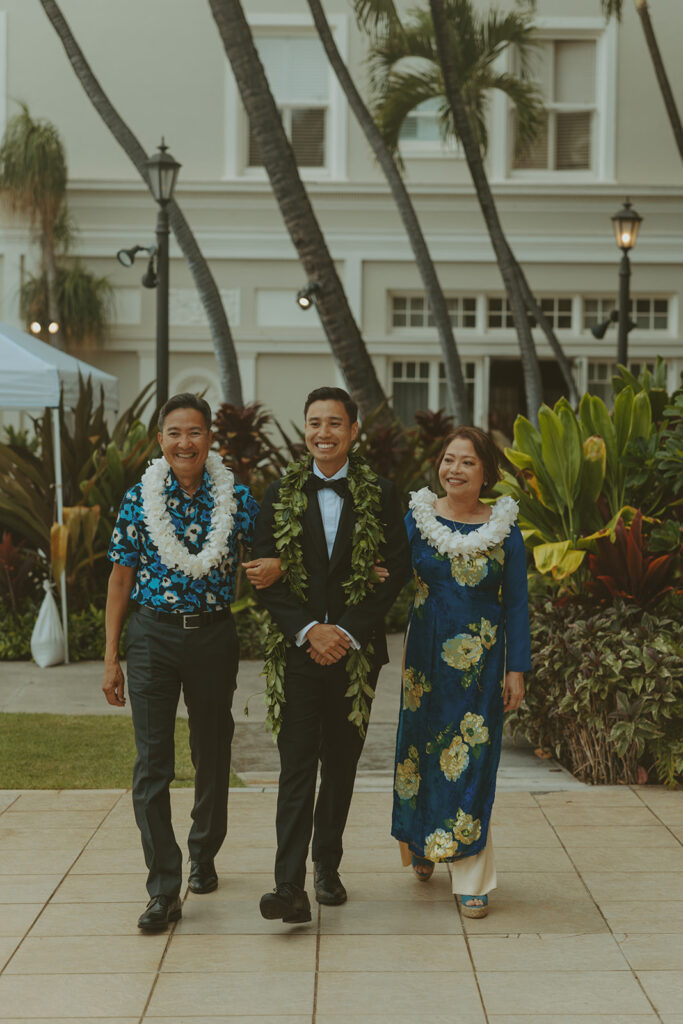 Outdoor wedding ceremony with palm trees and guests seated.
