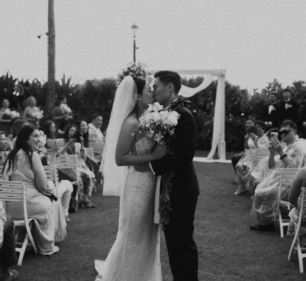 Outdoor wedding ceremony with palm trees and guests seated.

