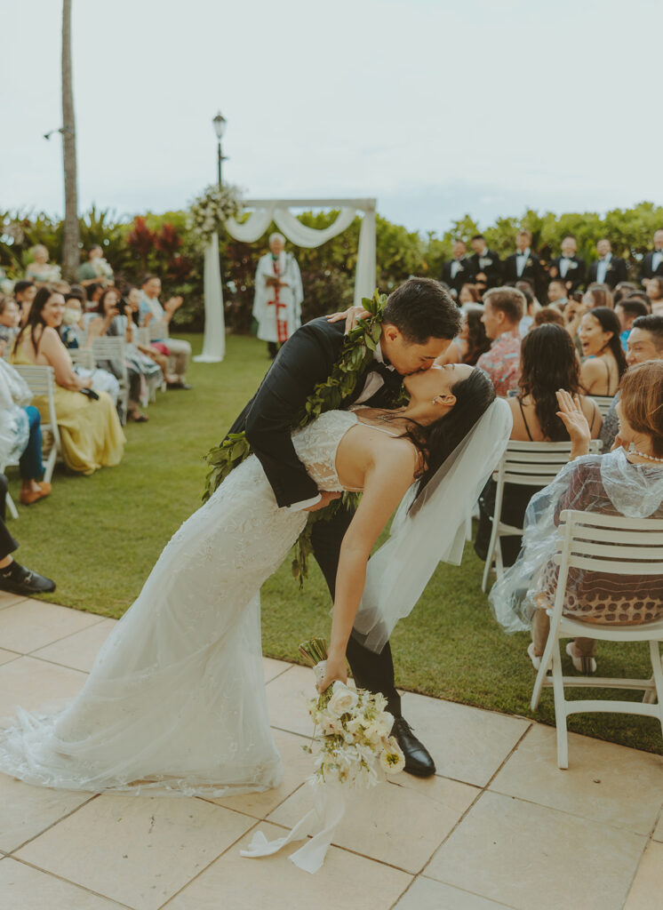 Outdoor wedding ceremony with palm trees and guests seated.
