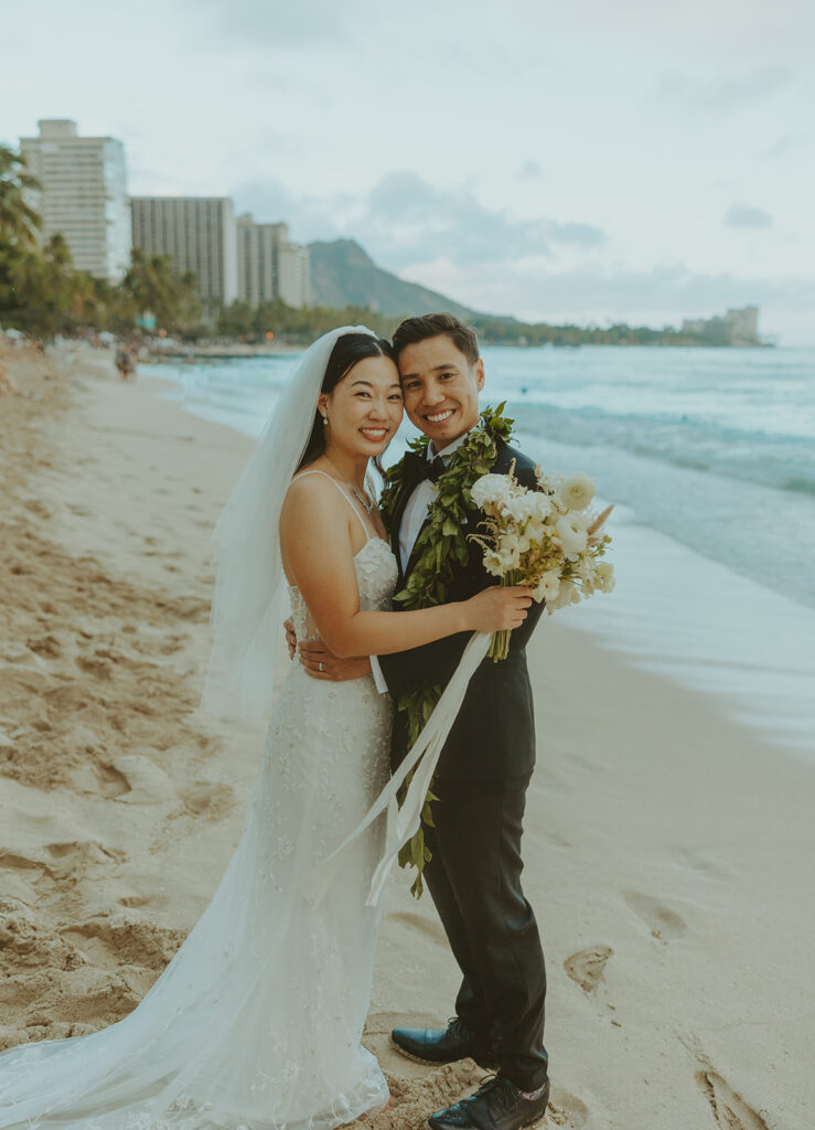Bride holding a bouquet of white flowers on the beach.
