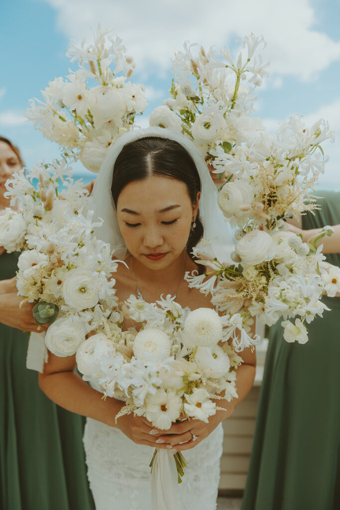 Bride smiling in a lace wedding dress and veil by the window. | Moana Surfrider
