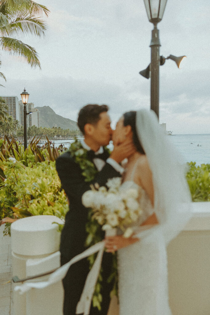 Bride holding a bouquet of white flowers on the beach.
